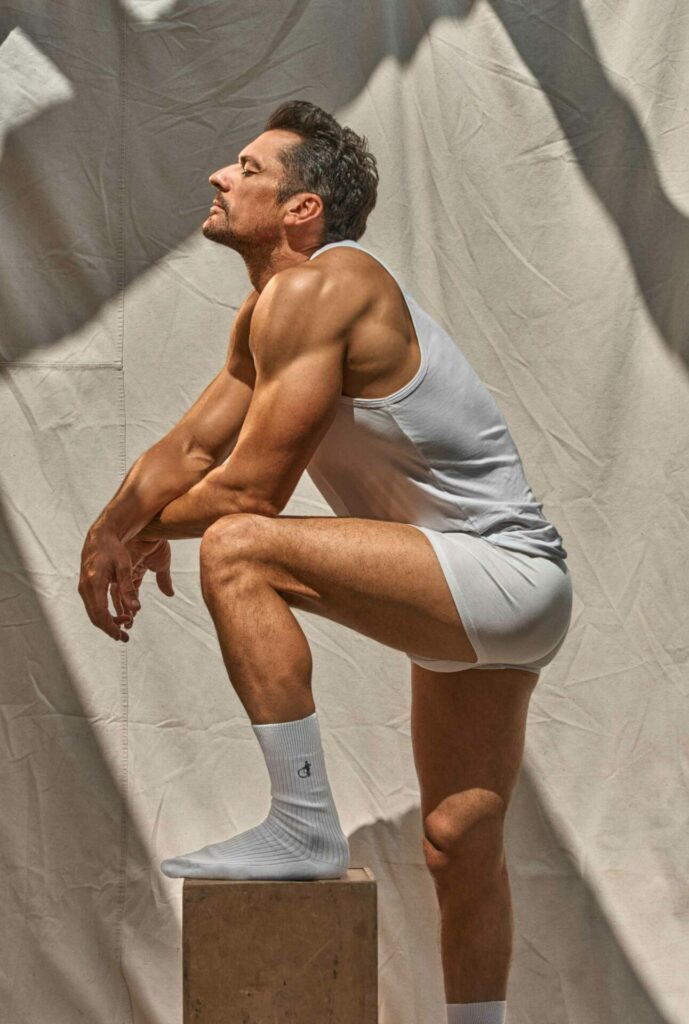 David Gandy wearing white trunks and a white vest with his leg resting on a pedestal