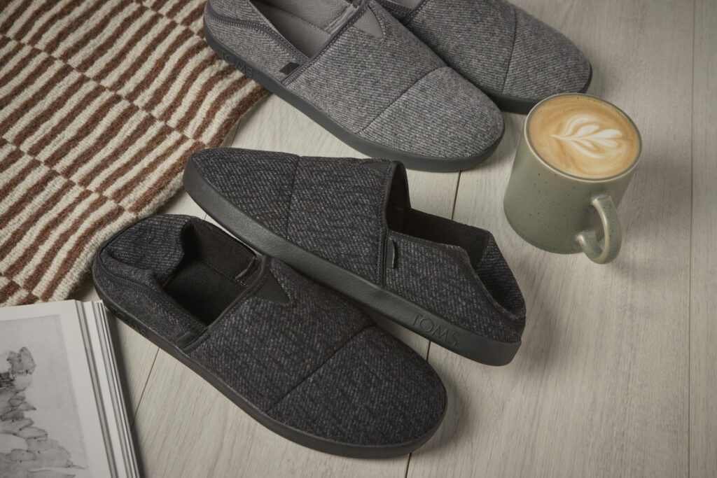 A lifestyle shot of the black and grey TOMS Camden slipper.