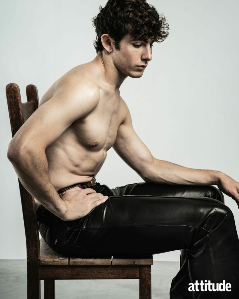 Model Edgar sits on a chair wearing leather trousers by AMIRI.