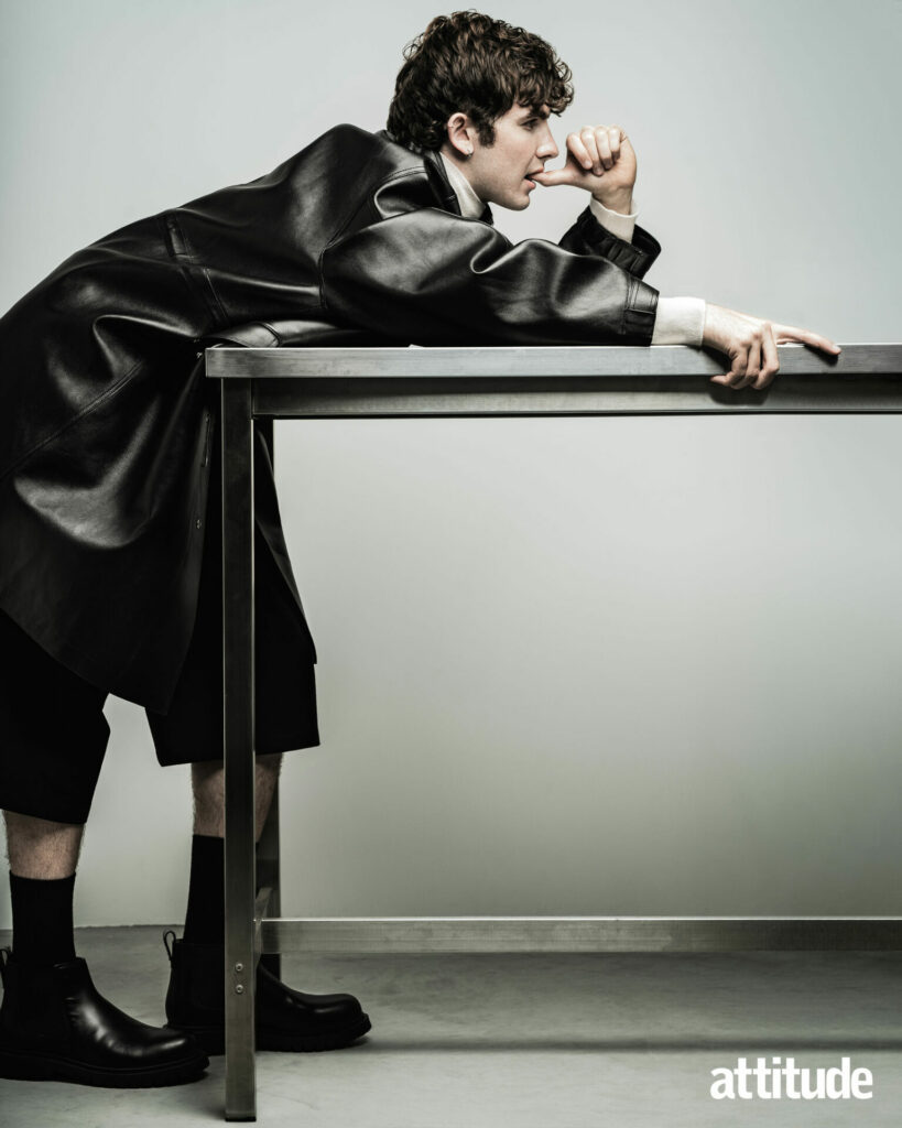Male model Edgar rests on a table wearing a leather jacket from Givenchy Autumn/Winter 2025.