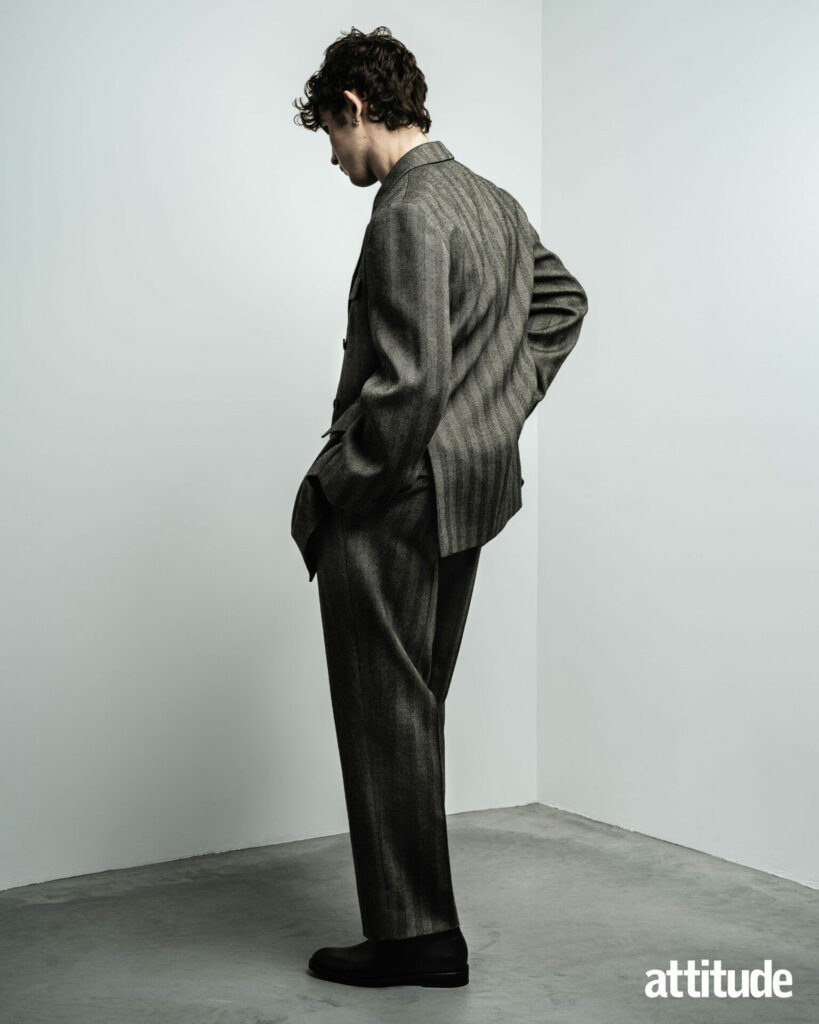 A model with his back turned to the camera wears a grey striped suit from Ferragamo.