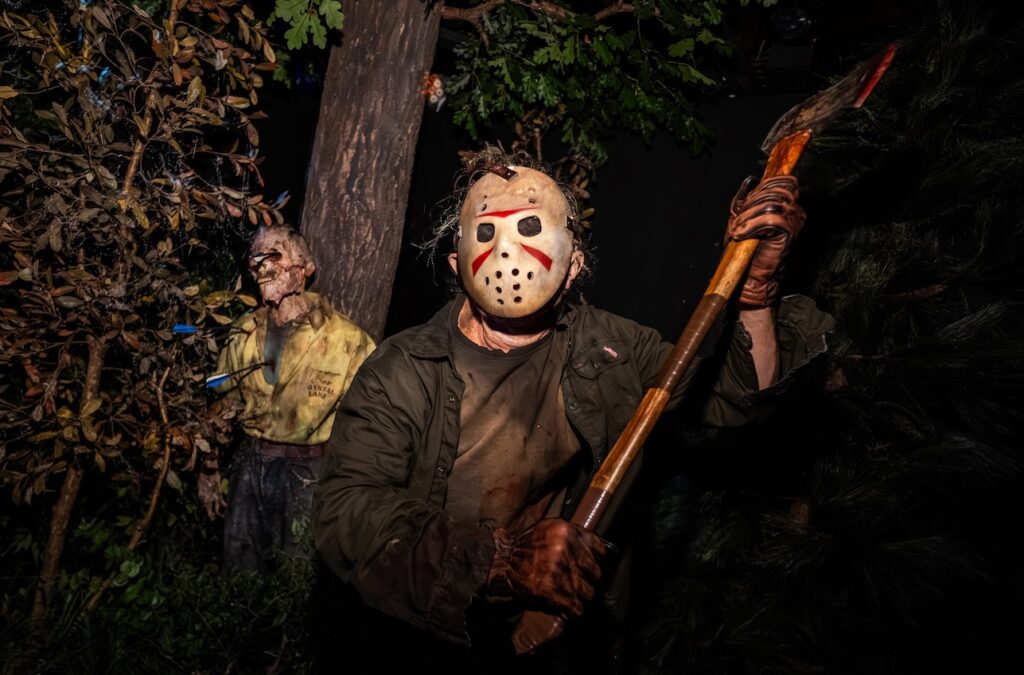 Friday the 13th's Jason Vorhees also make an appearance standing in  woodland holding an axe with a man affixed to a tree with arrows behind him