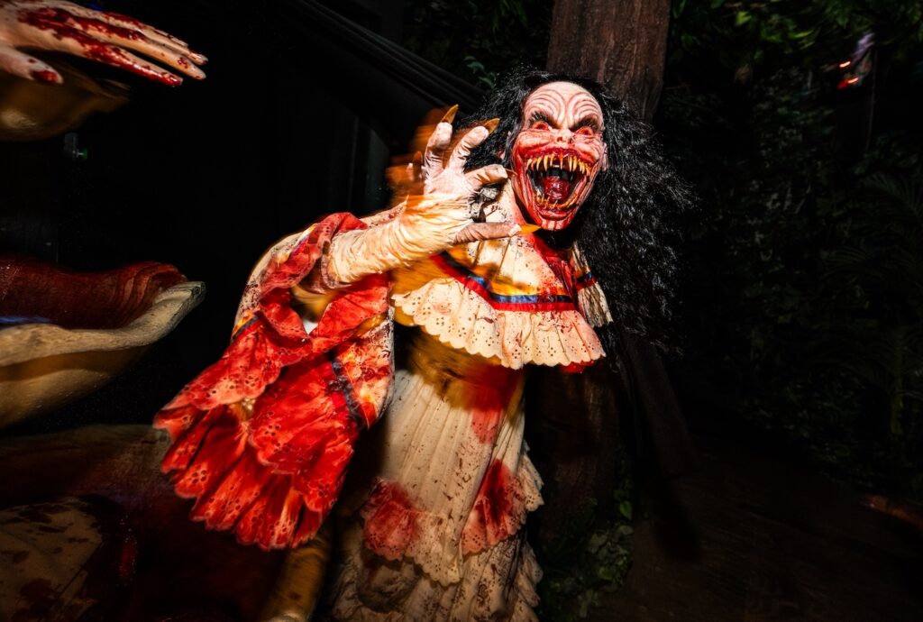 A monster from the Monstruos universe in a white dress and black hair, with sharp teeth on display