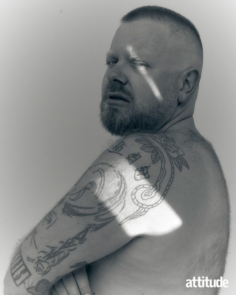 Ginny Lemon shirtless looking into the camera