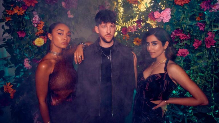 Leigh Anne, Sigala and Jonita Gandhi standing against a wall of flowers