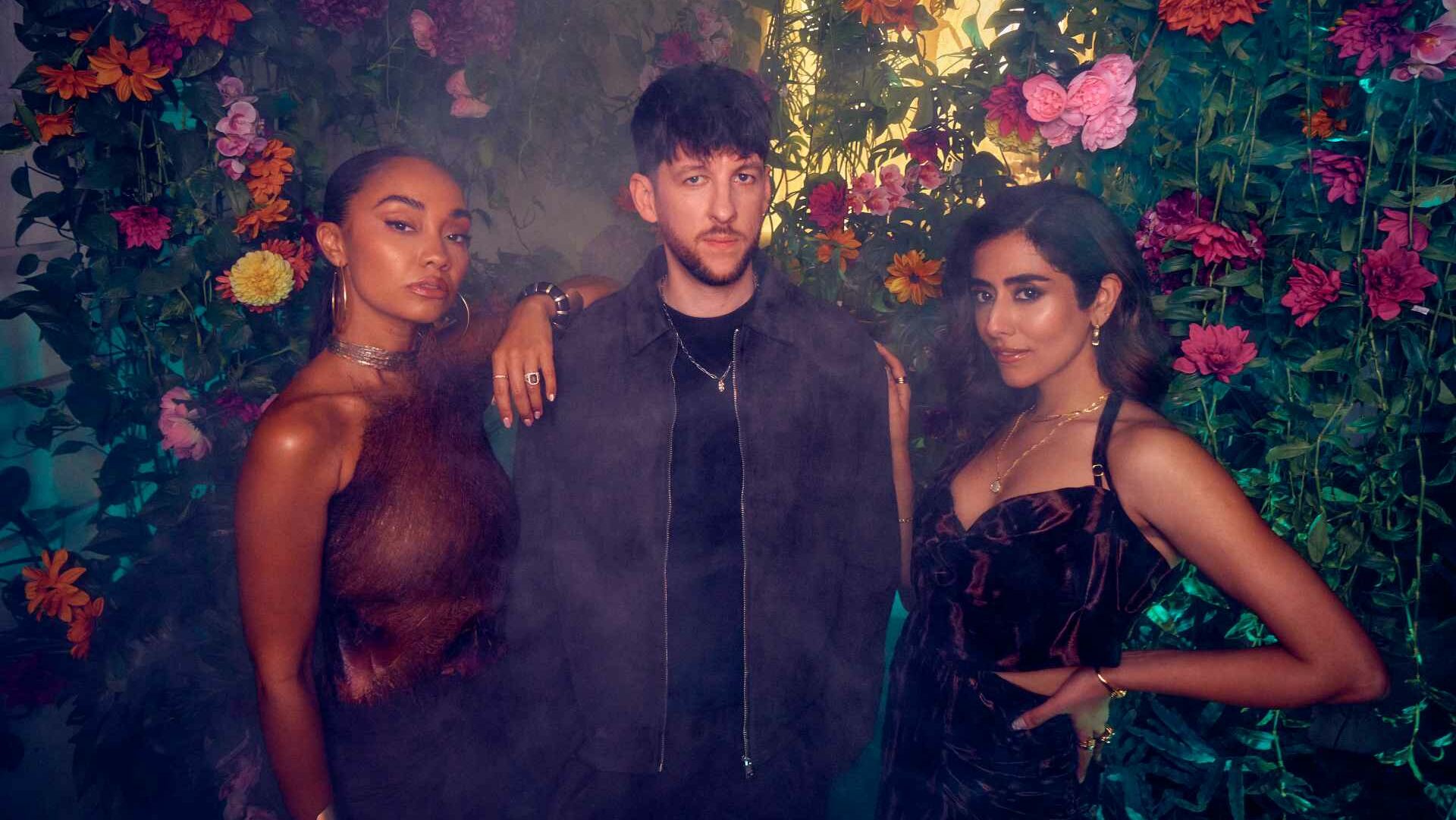 Leigh Anne, Sigala and Jonita Gandhi standing against a wall of flowers