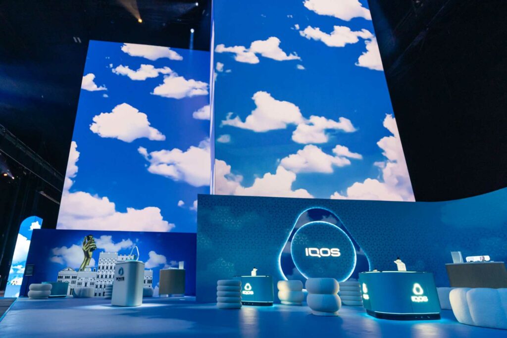 An LED Installation with blue sky and cloud projections featuring IQOS display stands