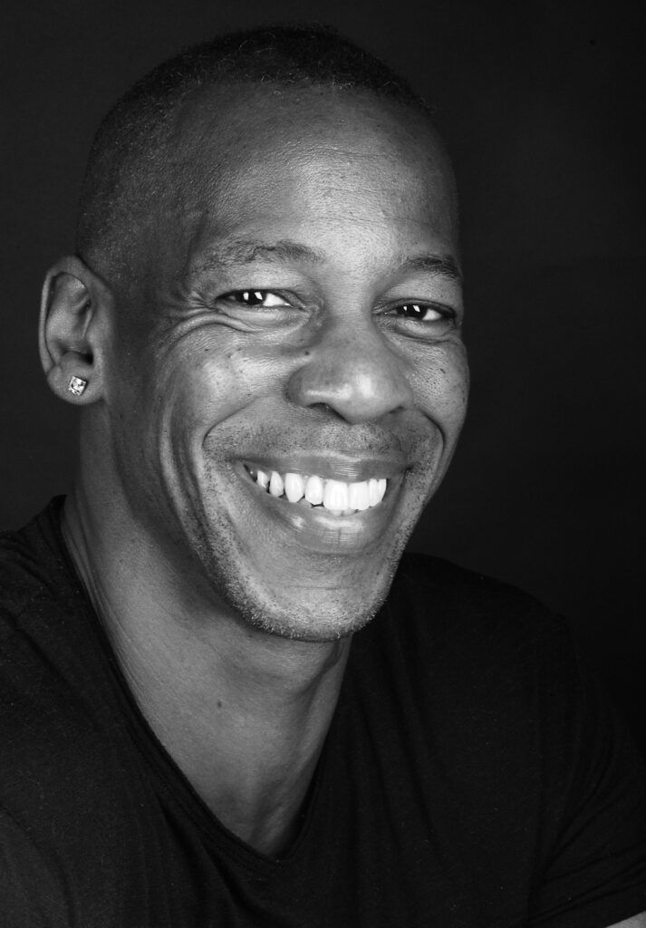 head and shoulders shot of Topher smiling, black and white