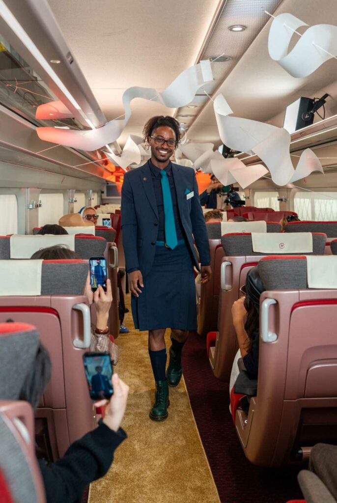 Eurostar staff member smiling while walking down the train aisle.