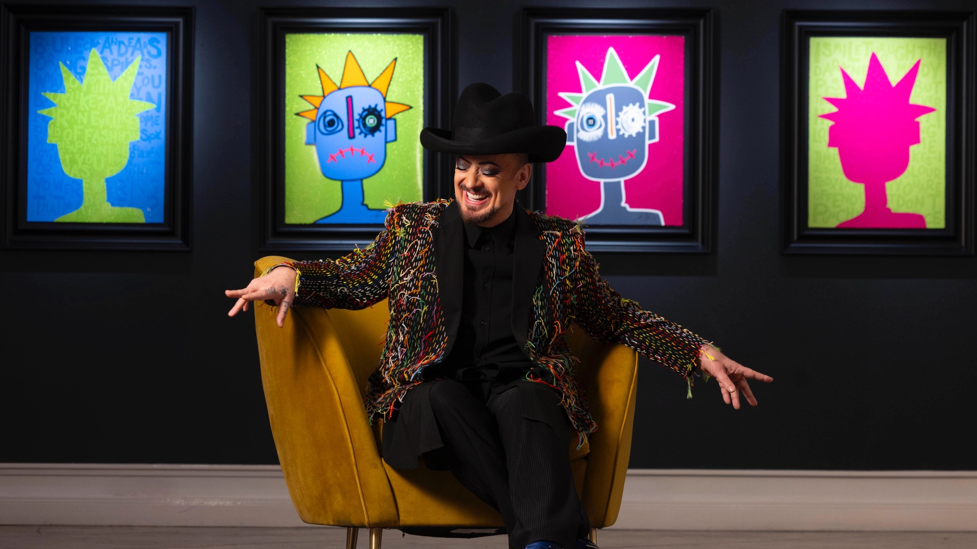 Boy George posing against his artwork