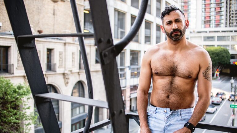 Alan Adolfo, a model in the new issue of Elska - topless, in jeans, bearded, standing on a stairwell in a city