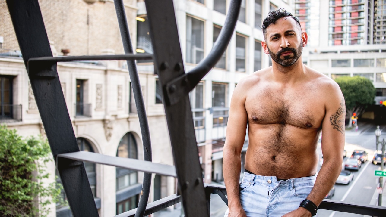 Alan Adolfo, a model in the new issue of Elska - topless, in jeans, bearded, standing on a stairwell in a city