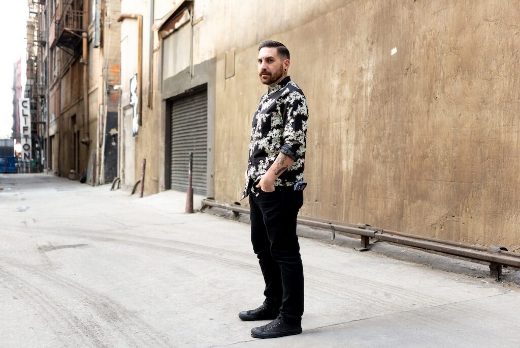 Jeremy Lucido, in black trousers and white and black floral short, standing on a street (Image: Elska/Liam Campbell)