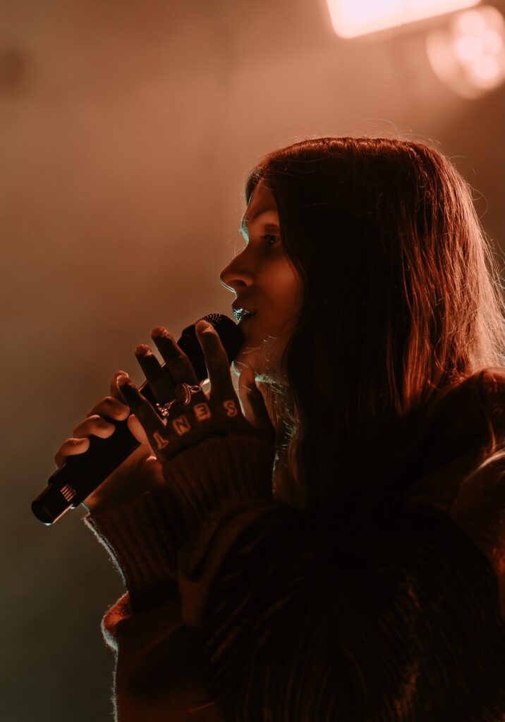 Ethel Cain close up, holding mic by mouth