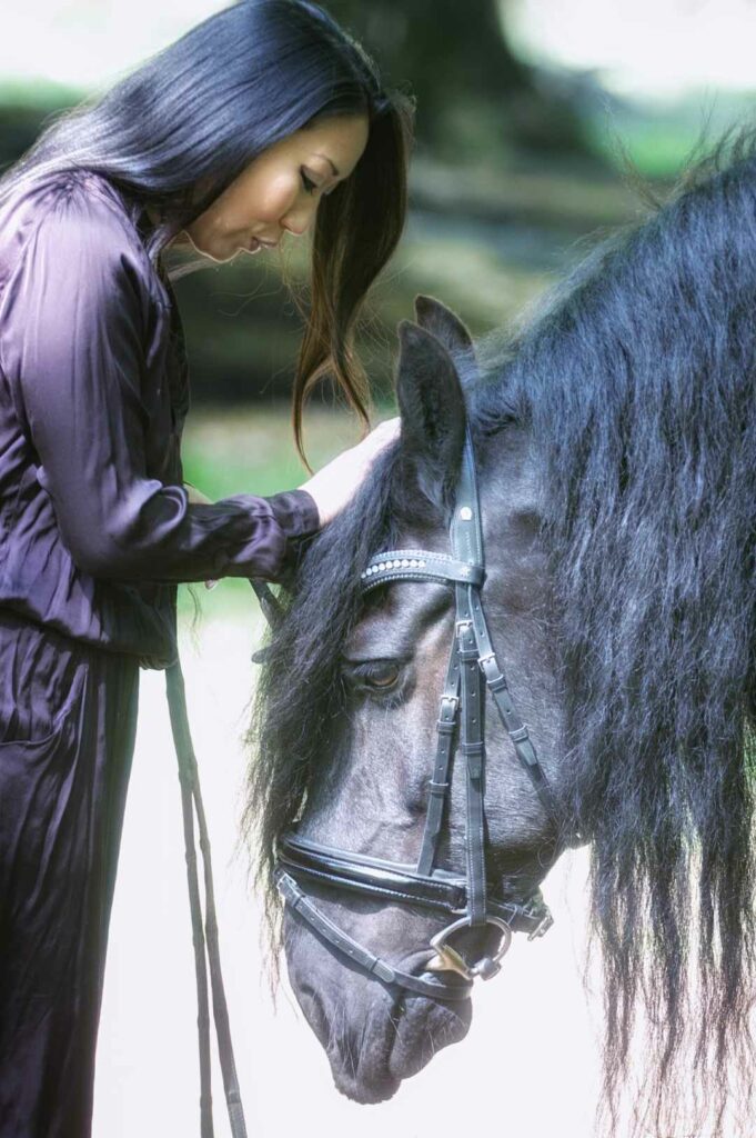 A woman with black hair petting a horse