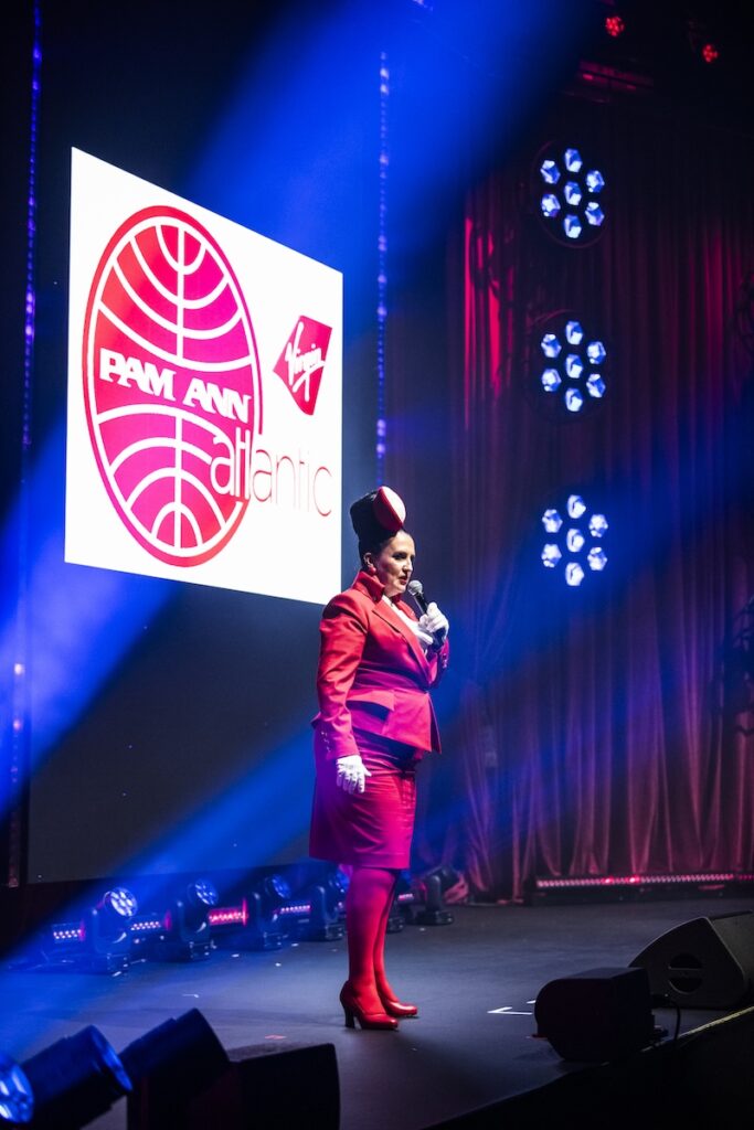 Pam Ann on stage in red aviation outfit