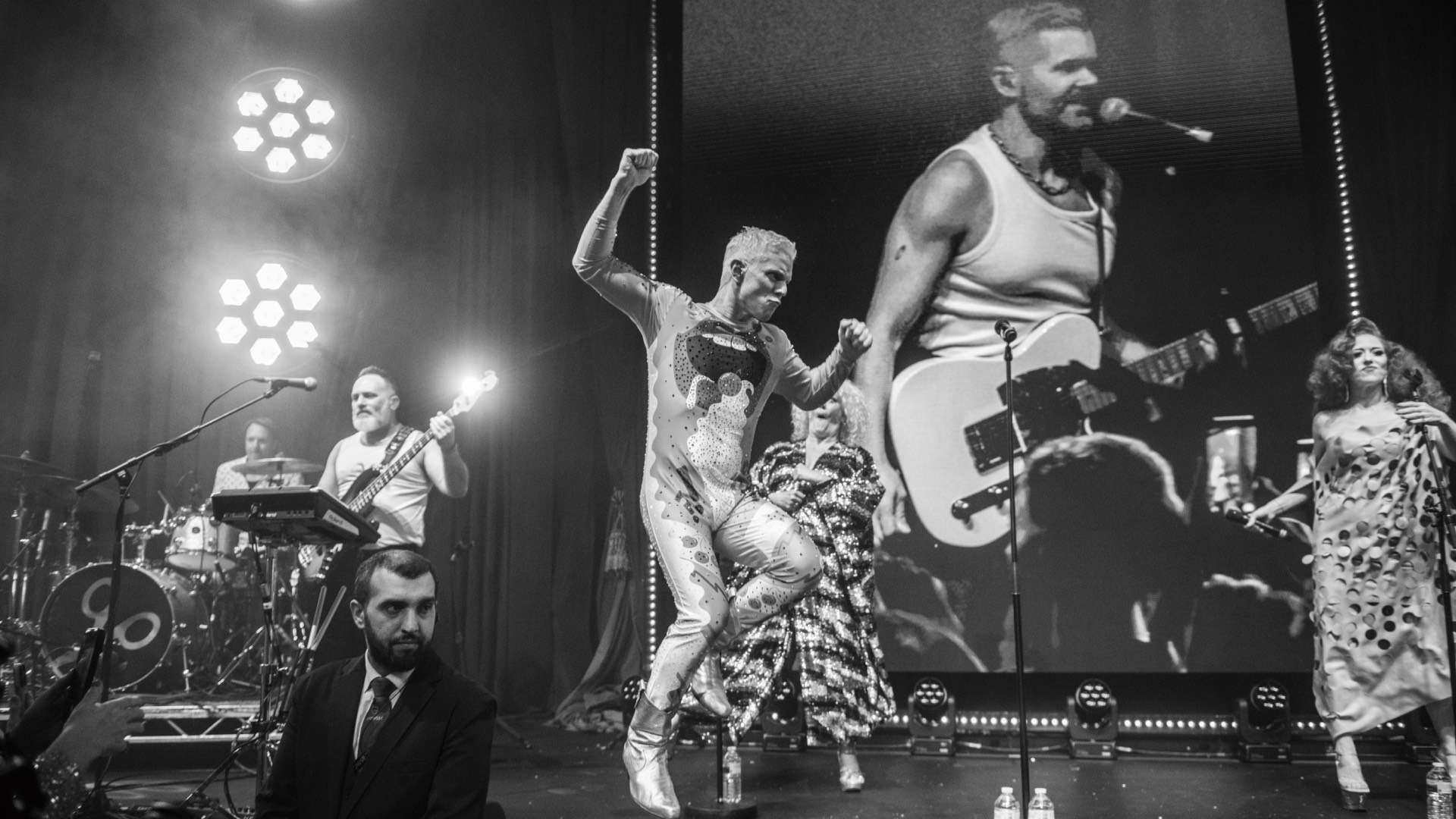Scissor Sisters performing at last night's Attitude Awards, black and white, Jake leaping and a nonplussed security guard in the front (Image: Attitude/Aaron Parsons)