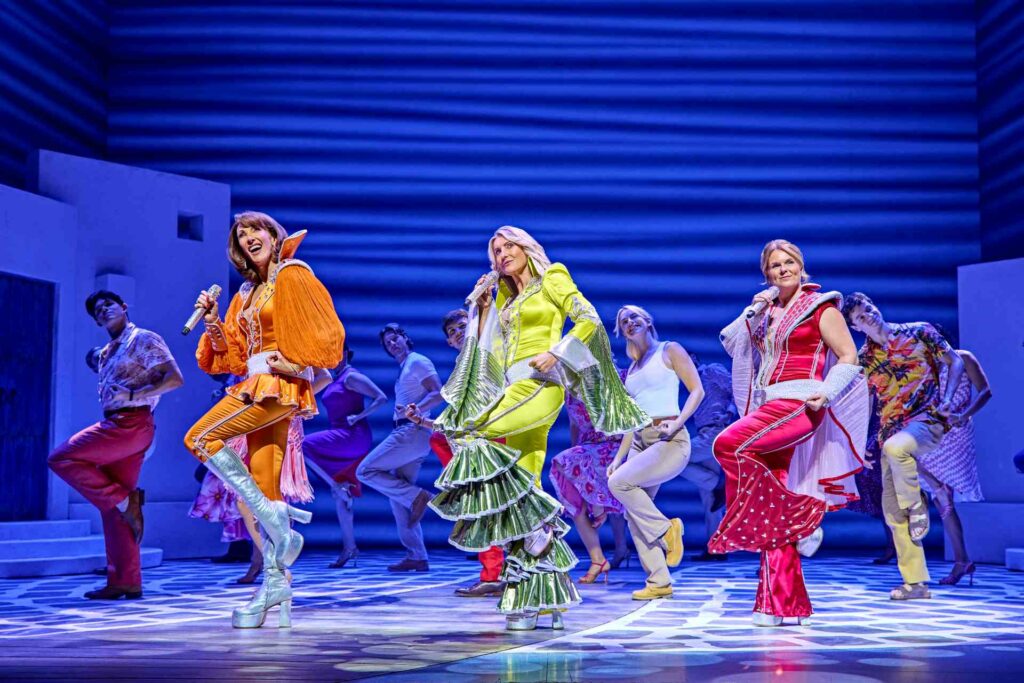 Cast performing a colourful dance number in Mamma Mia!