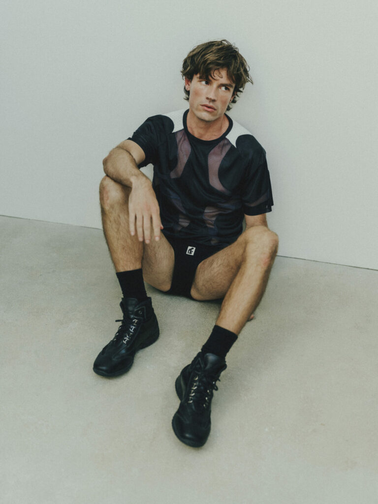 A lifestyle shot of a model wearing a mesh panel t-shirt from EricAf Drop 003