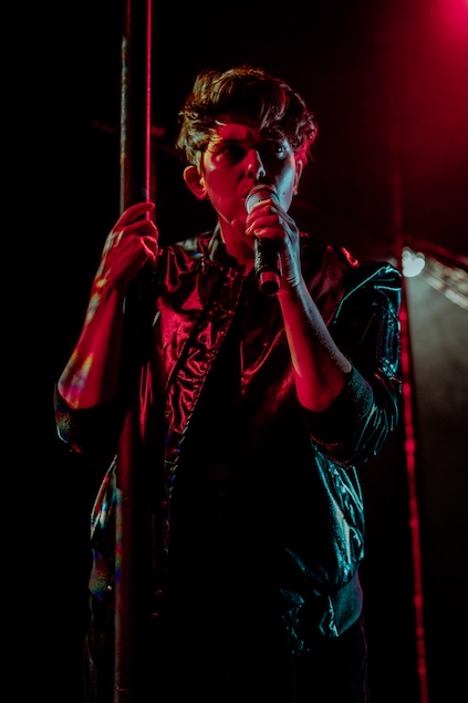 Transpose: SUBVERSE performer with a microphone lit by a red light