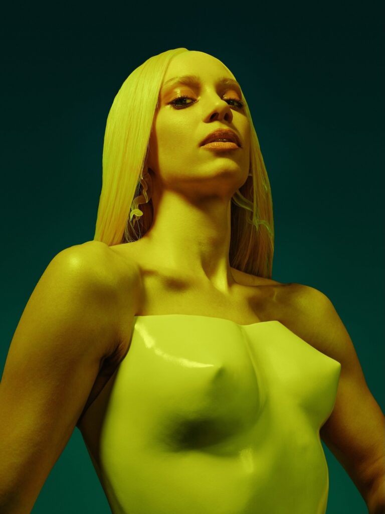 Agnes in a lime green breastplate with long blonde hair