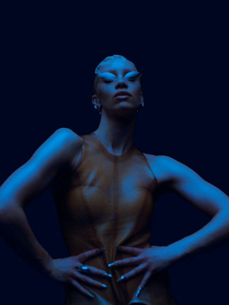 agnes in orange top lit by a dark blue light