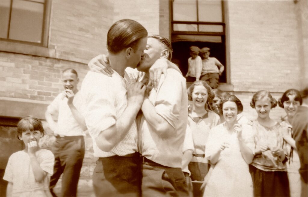 a male couple kissing while onlookers smile