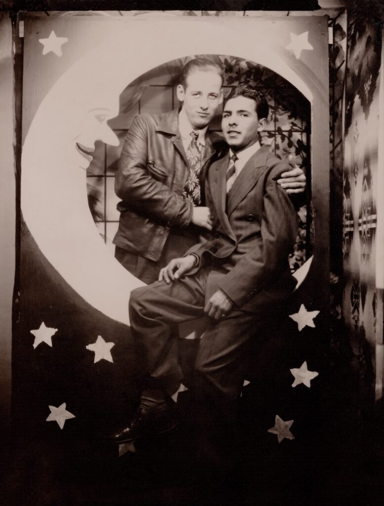 a male couple in suits posing with a moon and stars backdrop