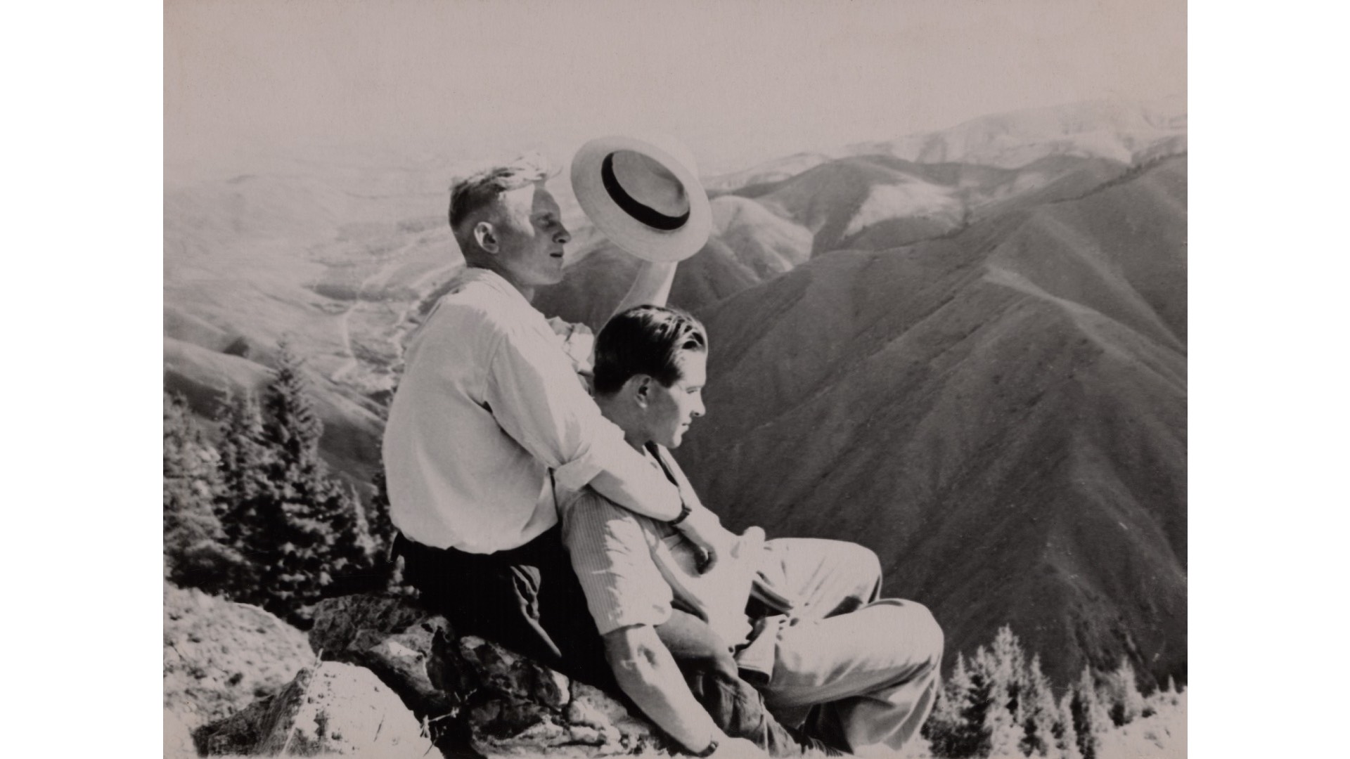 a couple lying on rocks and holding each other and sitting on the top of a mountain