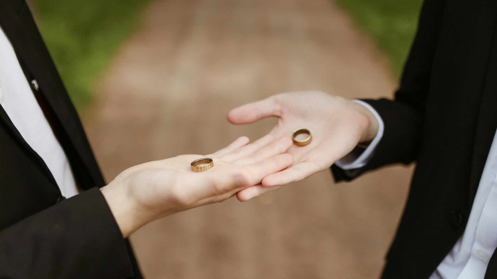 two grooms holding wedding rings