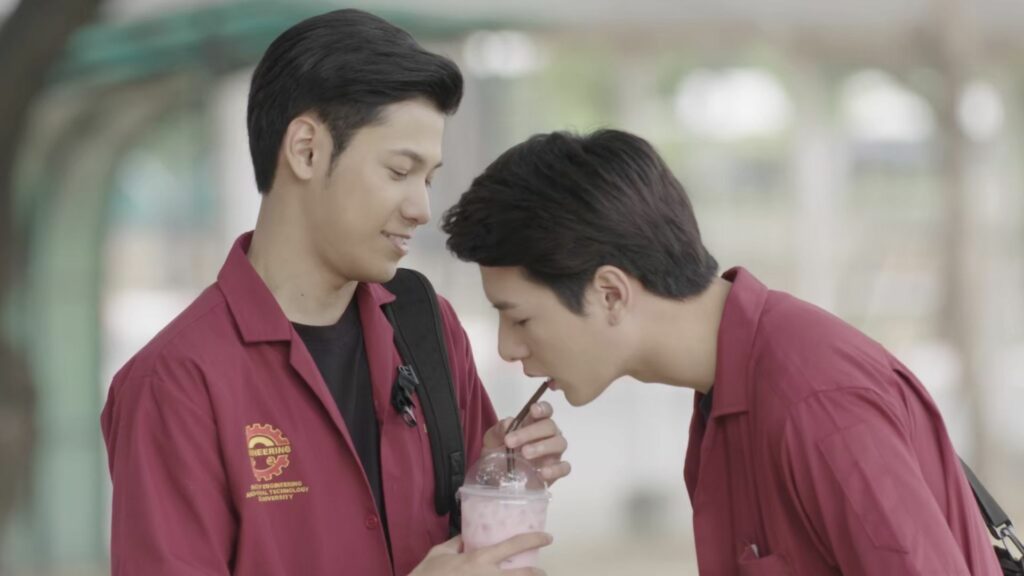 A man drinks from a straw held by another man in Thai BL series SOTUS