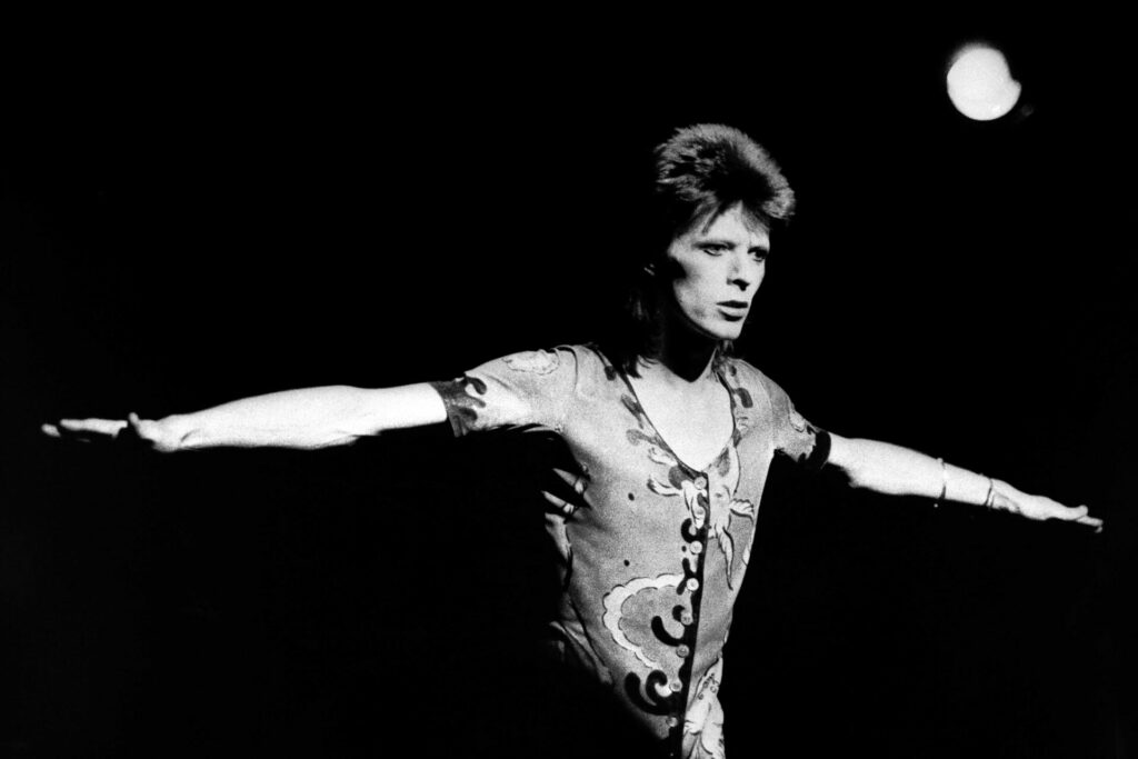 David Bowie black and white with his arms stretched out to his sides 