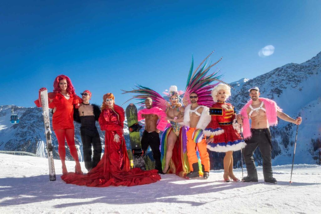 Drag queens and men standing on a skiing slope