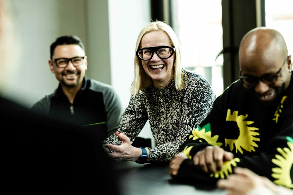 A group of colleagues sitting around a table laughing 