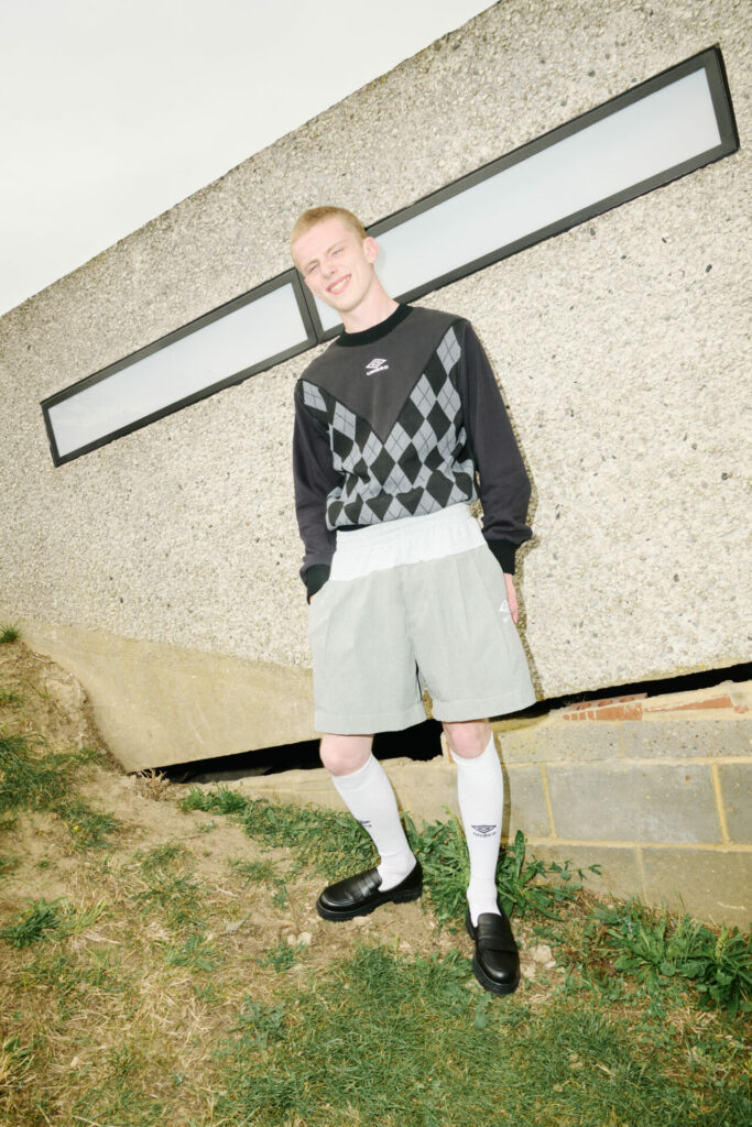 A model wears an Argyle pattern crewneck jumper from the collaboration between Adam Jones and Umbro