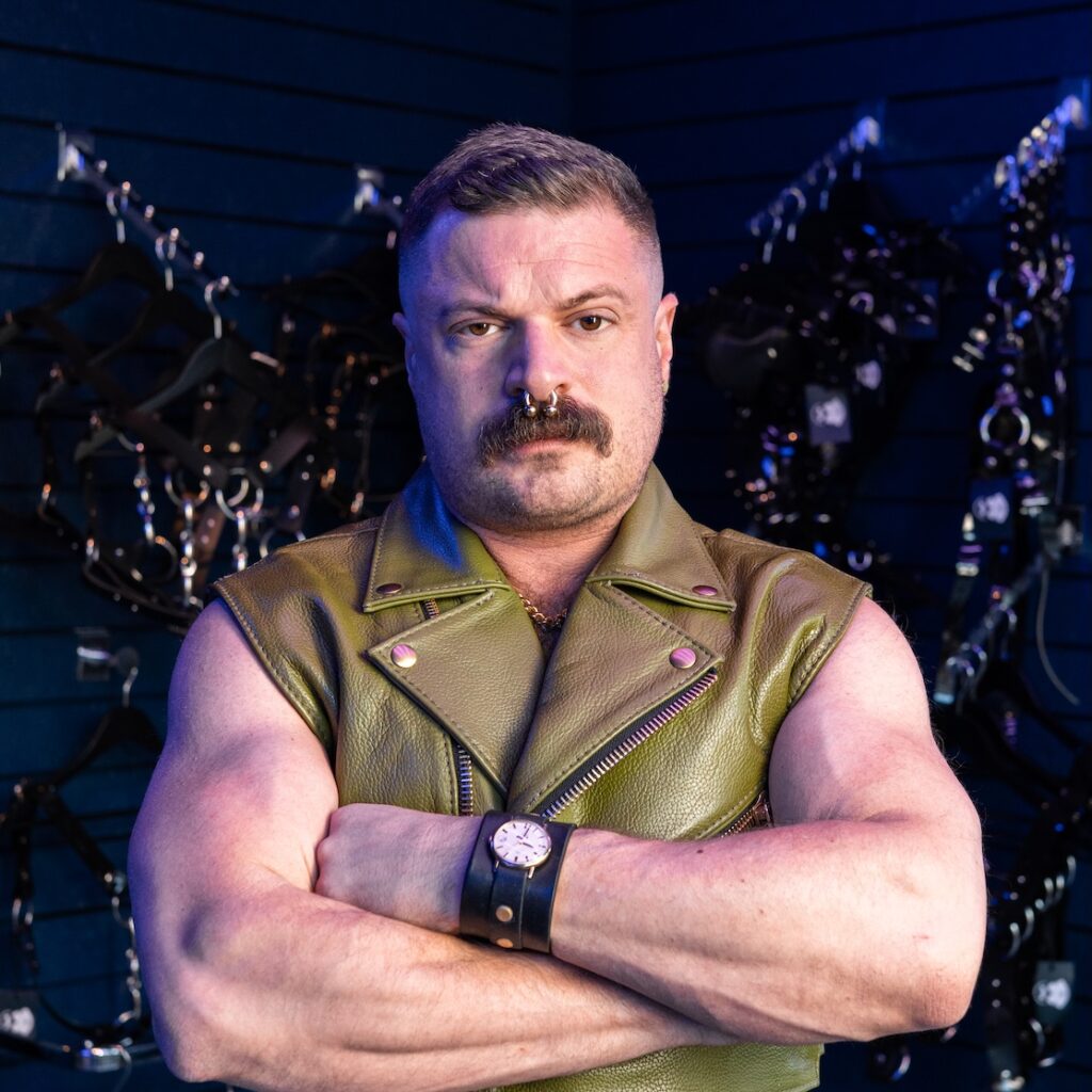 the interviewee in a sleeveless green leather vest with arms folded