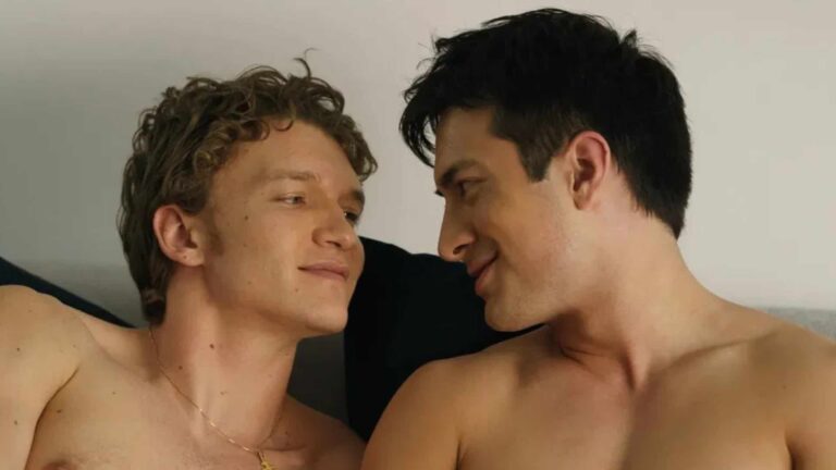 Two shirtless men kissing in bed