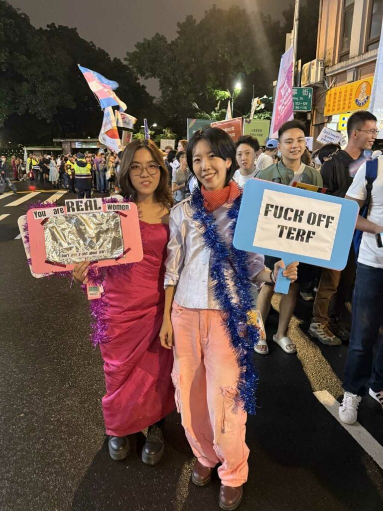 Two people at the Trans March at Taiwan Pride 2025 holding signs saying FUCK OFF TERF and You are REAL women