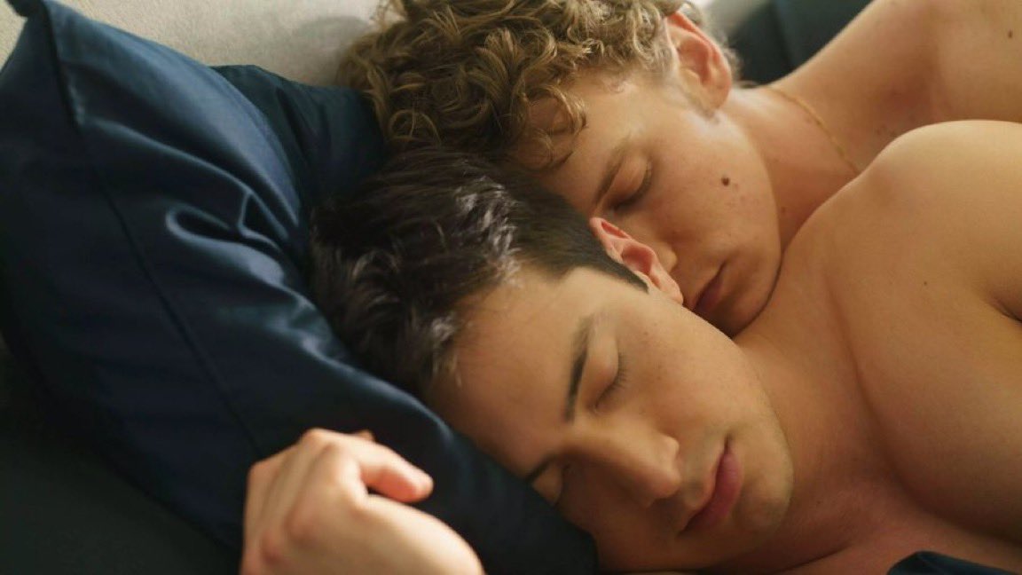 Hudson Williams and Connor Storrie cuddling in bed