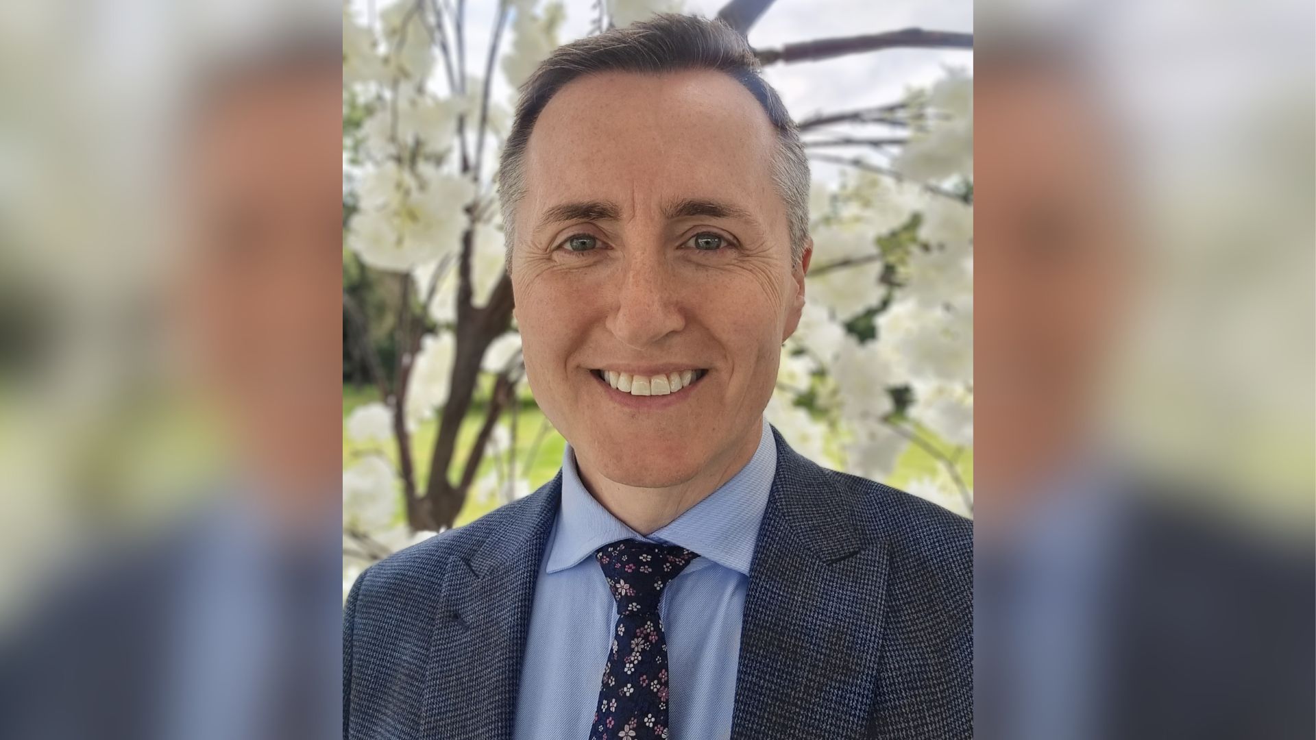 A smiling man in a blue suit and tie