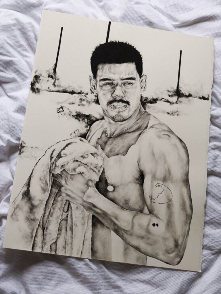 a work of the artist topless holding a towel, the piece laid on a white sheet