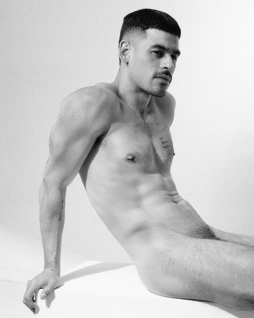 the artist sitting topless in a studio, black and white