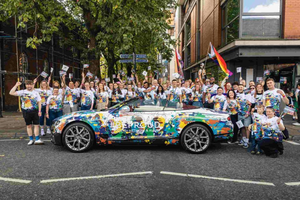 A group of Bentley colleagues standing around a Pride-themed Bentley car at Manchester Pride 2024