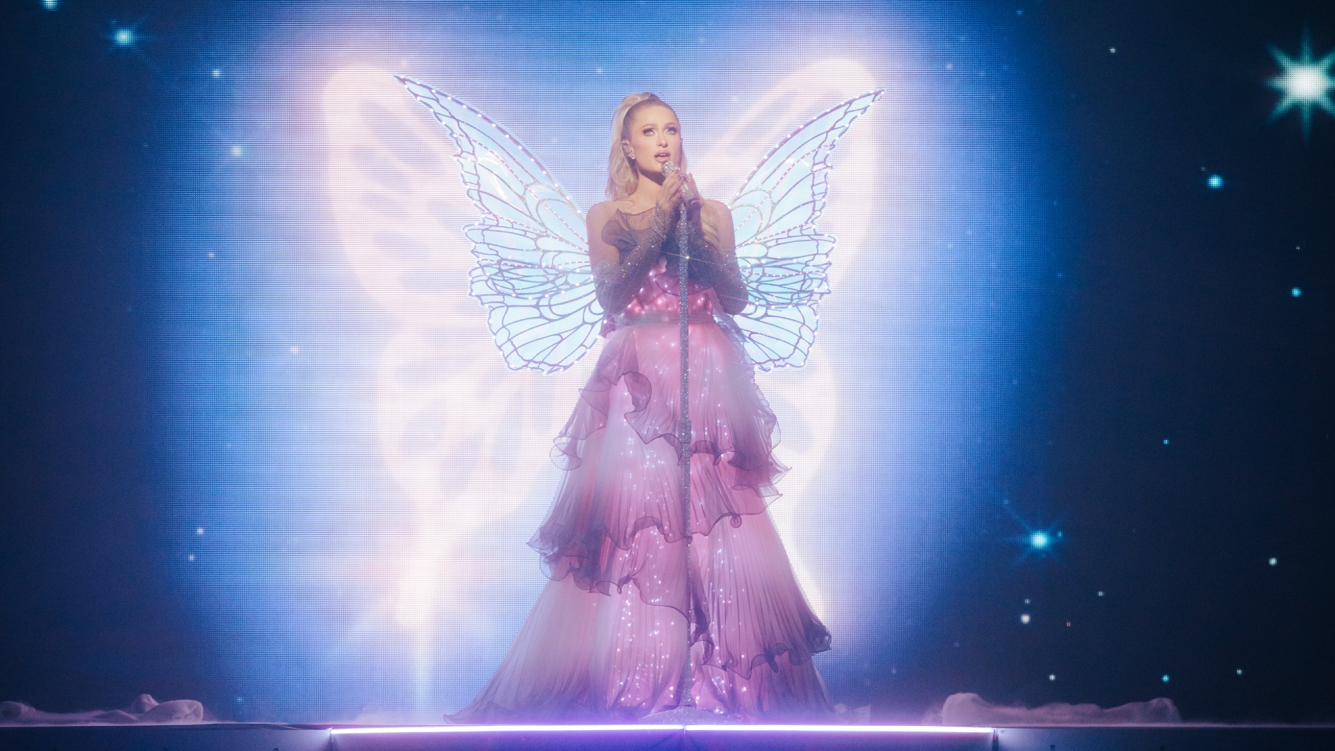 Paris Hilton in Infinite Icon: A Visual Memoir, a still, on stage in fair outfit