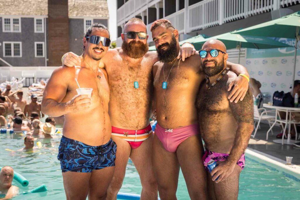 Four people posing together at a pool party during Bear Week in Provincetown.