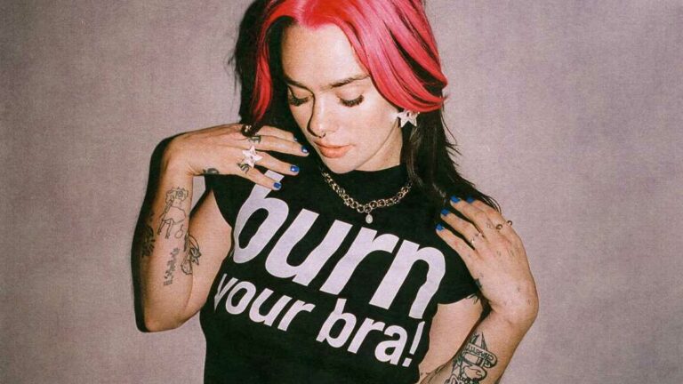 A woman with pink hair wearing a T-shirt that says burn your bra on it