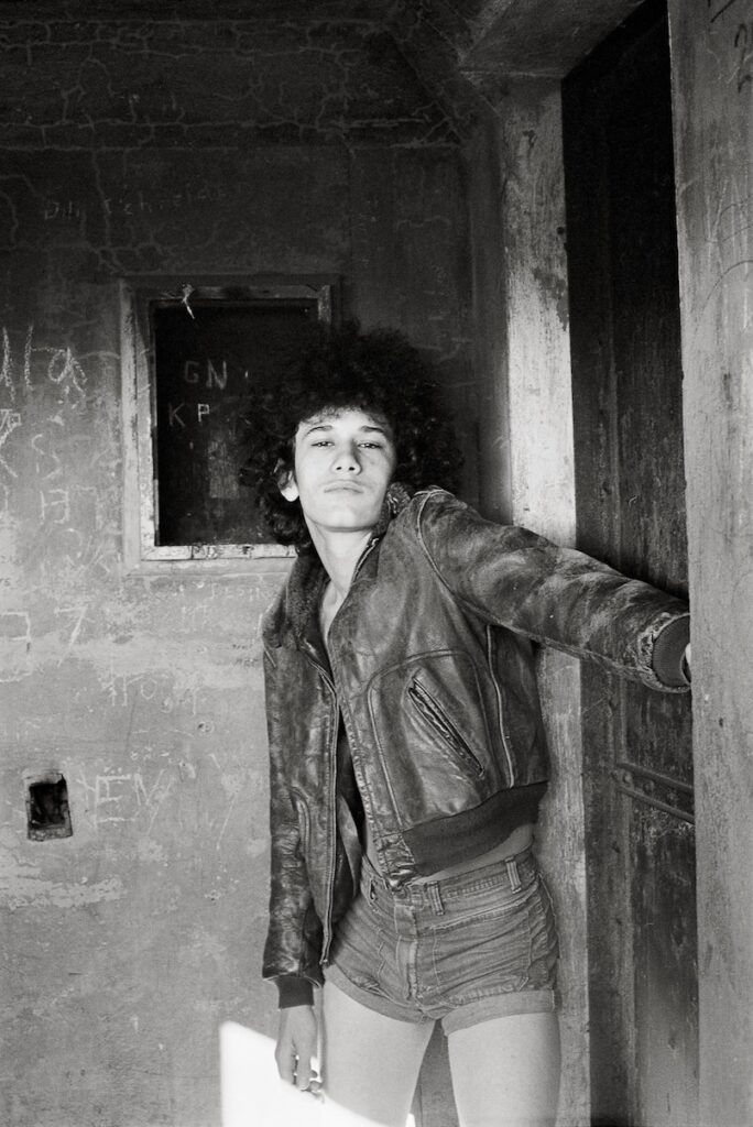 the subject, Myla, in denim shorts and a leather jacket standing in a doorway