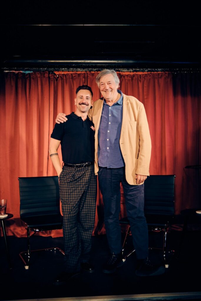 Andrew Keates and Stephen Fry in-front of a red curtain