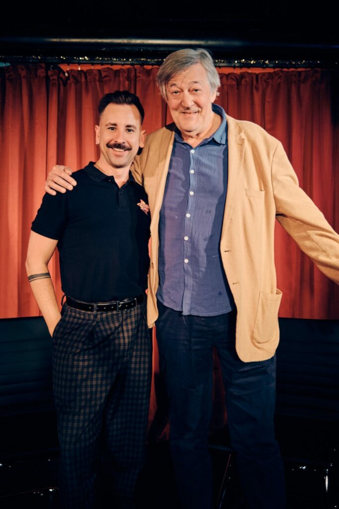 Andrew Keates and Stephen Fry in-front of a red curtain