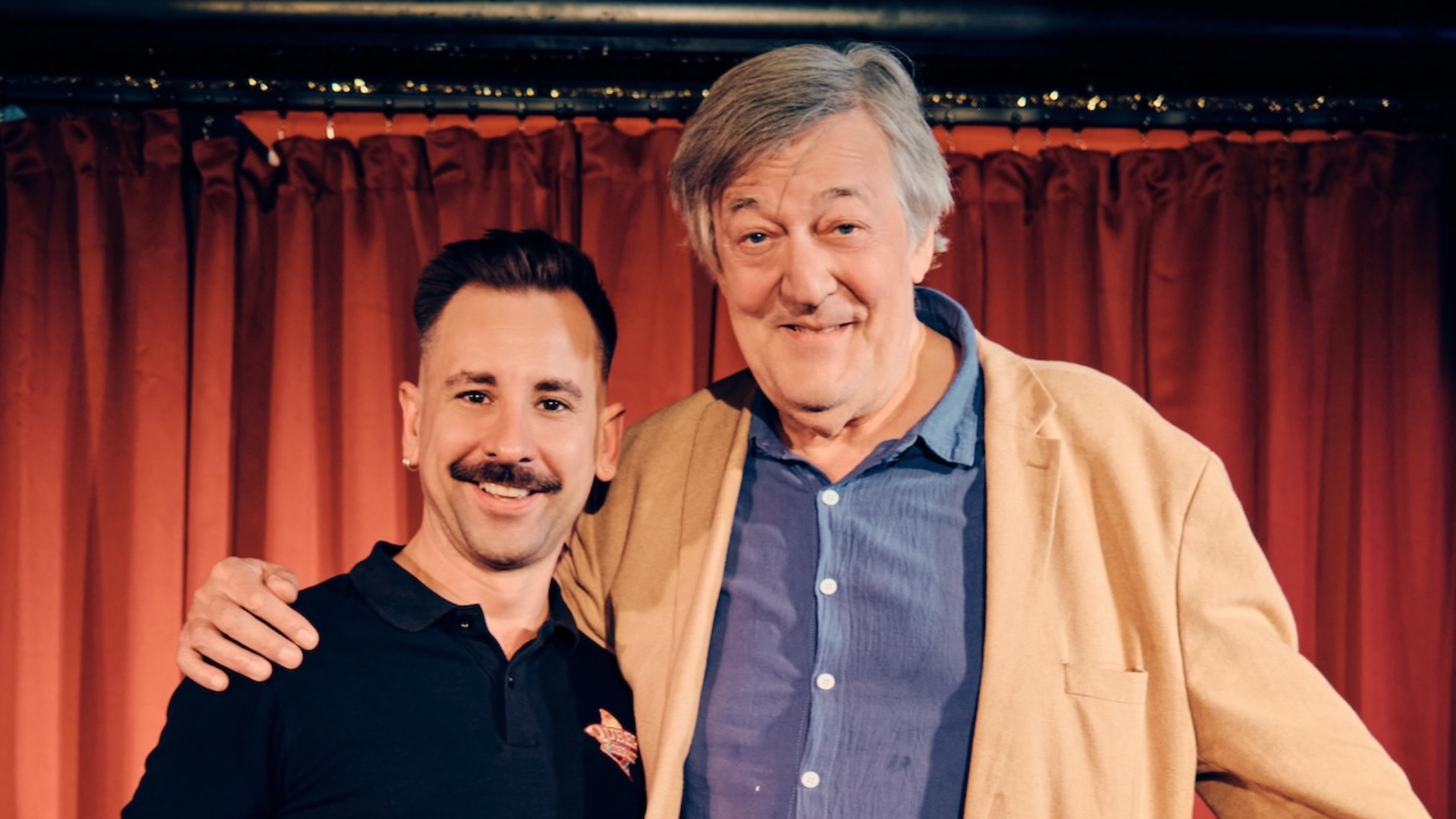 Andrew Keates and Stephen Fry in-front of a red curtain